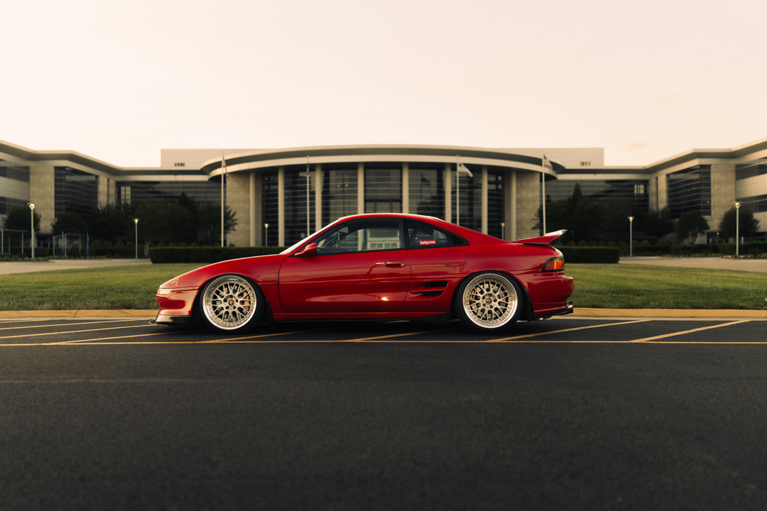John Santos 1991 Toyota MR2 SW20 Ferrari Red side profile with Work VS-XX wheels parked in urban setting