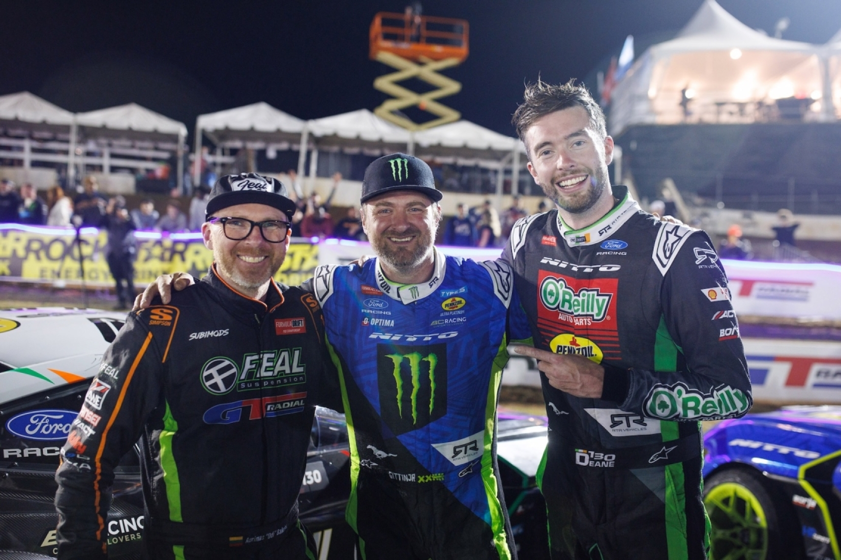 Vaughn Gittin Jr, Ryan Bakchis, and James Deane celebrate on the podium after Formula Drift Round 2 at Road Atlanta