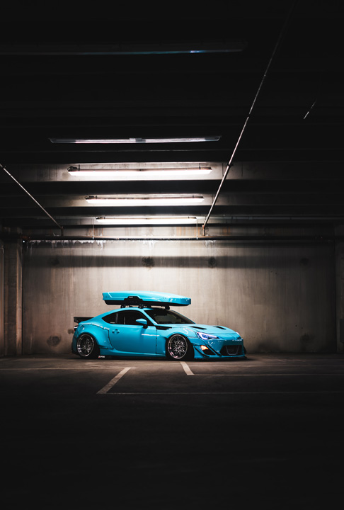 Rear three-quarter view of Nicholas Sargeant’s widebody Scion FR-S inside a dimly lit parking garage.
