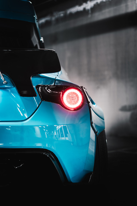 Widebody Scion FR-S with Rocket Bunny V2 kit, custom paint, and roof-mounted ski box in a parking garage.