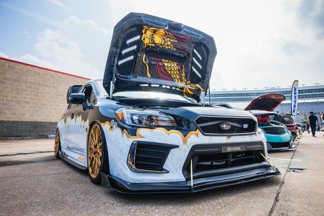 Modified Subaru WRX STI with custom artwork and an illuminated hood display showcased at FuelFest Dallas-Fort Worth.