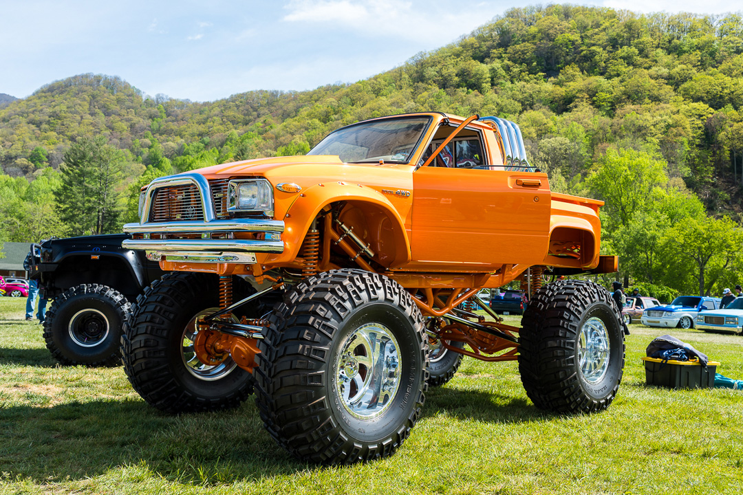 Bright orange lifted classic mini truck with oversized off-road tires on display at Mini Truckin’ Nationals.