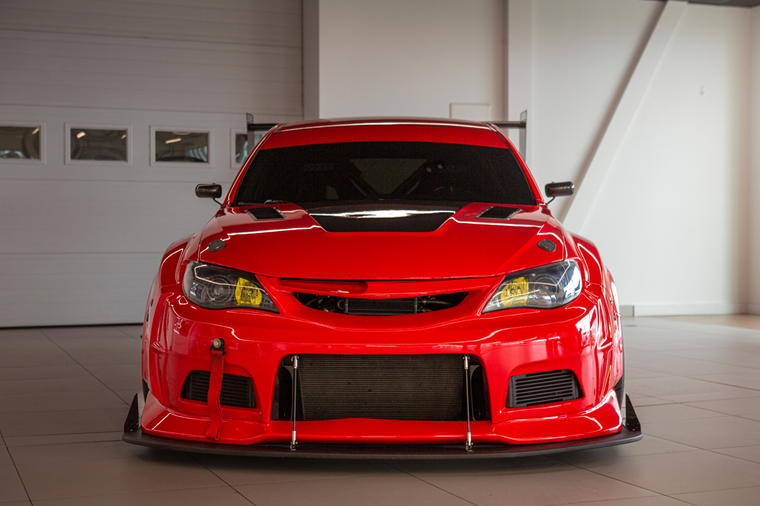 Jon Erickson’s red LS-swapped 2011 Subaru STi with widebody aero and track-focused details.