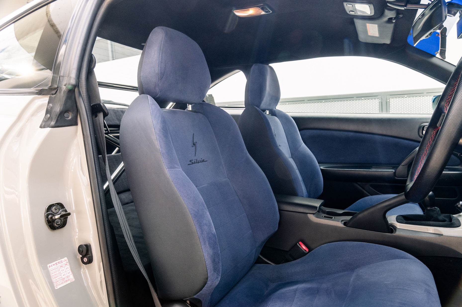 Interior detail of Bill MacKenzie’s 2000 Nissan Silvia S15 showing the blue Option B seats, door cards, steering wheel, shifter, and clean cabin layout.