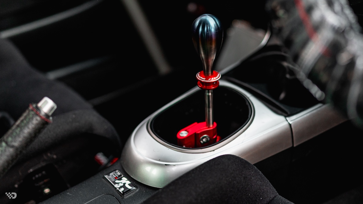 Interior detail of Moises Wynns’ 2003 Acura RSX showing the Hybrid Racing shifter, shift knob, center console, and right-hand-drive cockpit details.