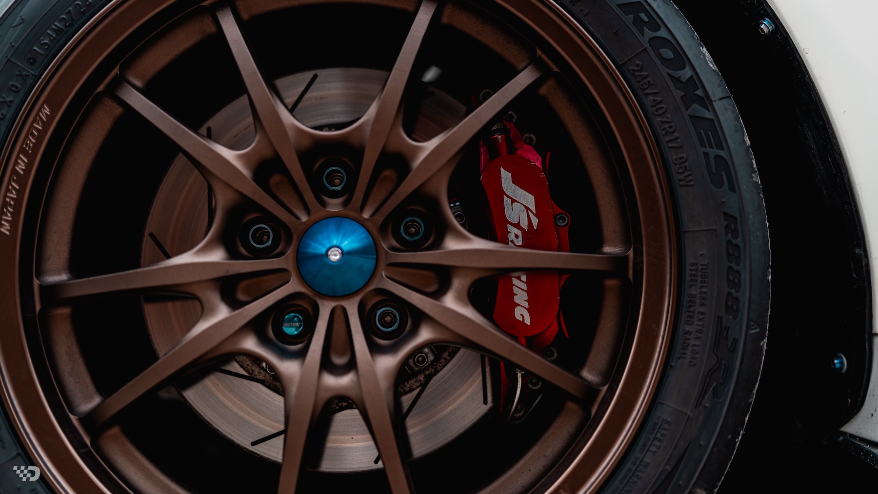 Close-up of Moises Wynns’ 2003 Acura RSX showing the bronze Mugen MF10 wheel, Toyo R888R tire, and red J’s Racing front brake caliper.