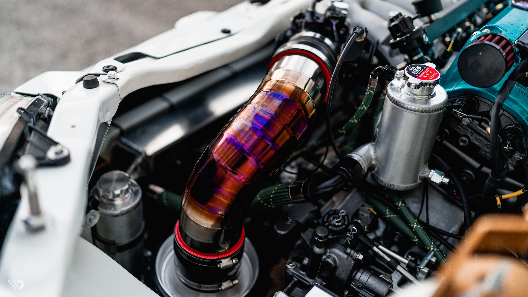 Close-up of Moises Wynns’ 2003 Acura RSX engine bay showing the titanium intake piping, custom cooling components, fuel lines, and detailed K-series hardware.