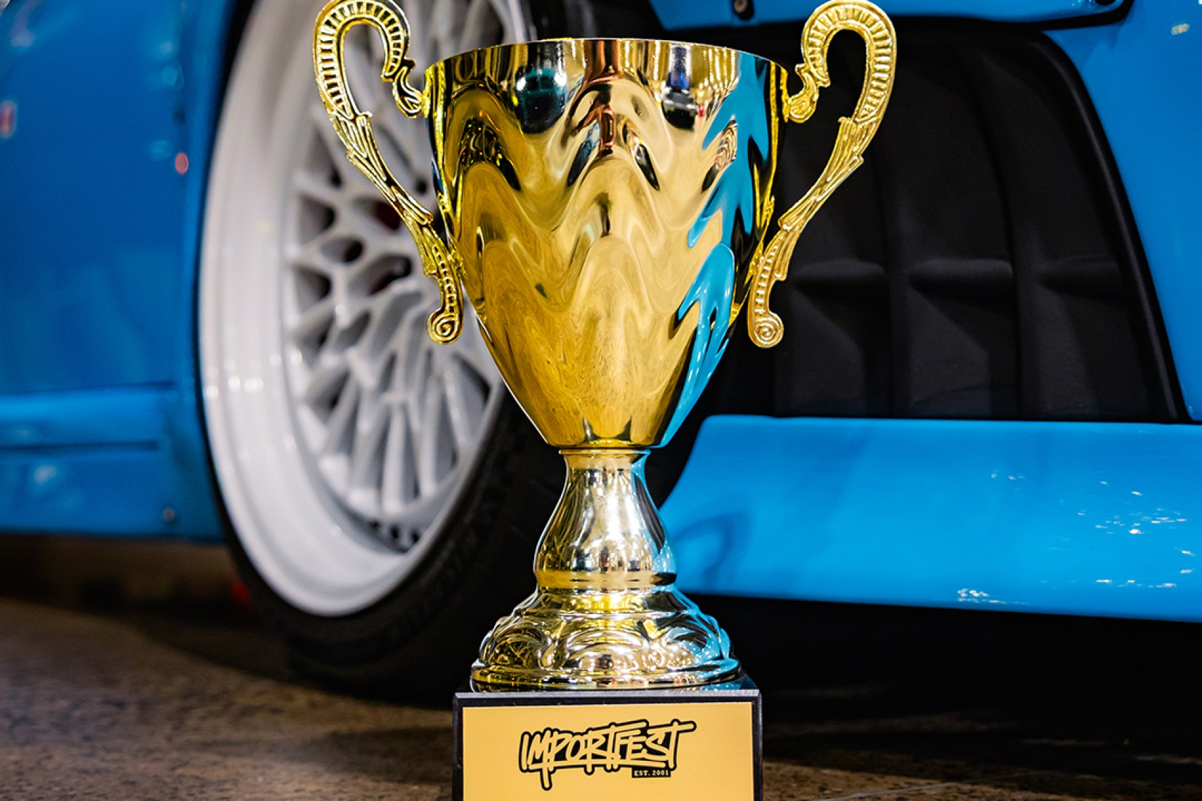 ImportFest trophy displayed in front of a modified blue car at ImportFest 2026 in Toronto.