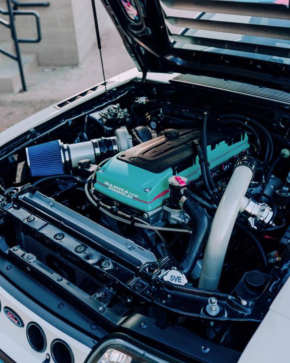 Regan McLaughlin’s 1988 Ford Mustang GT TimeFox with custom multi-tone paint, Ford Barra turbo swap, wide fiberglass fenders, retro Foxbody styling, HaloBLK wheel covers, custom interior, and nostalgic audio details.