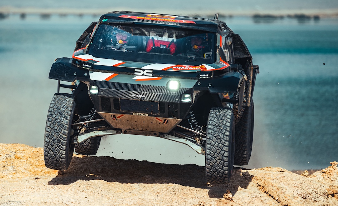 Dakar rally vehicle driving over rough terrain with Reiger suspension technology developed for off-road performance.