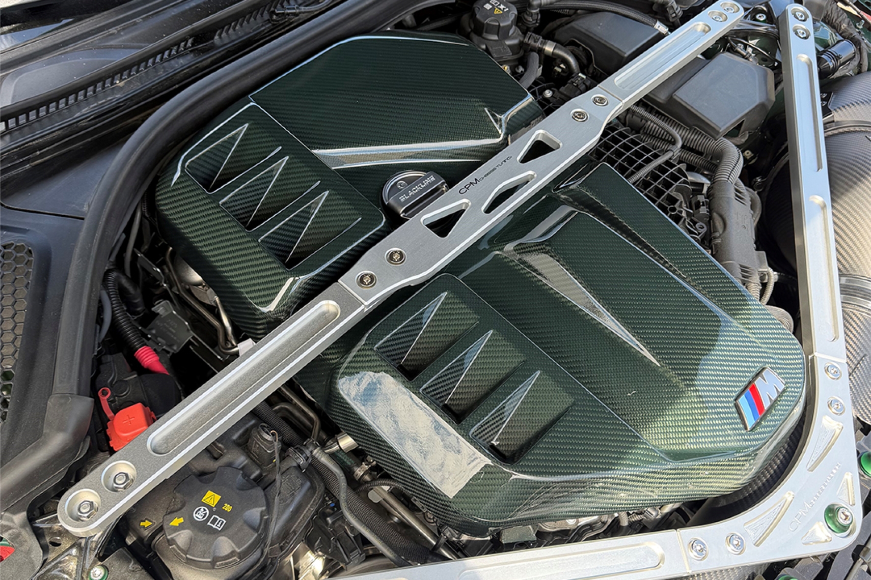 CPM Aluminum Front Upper Strut Brace installed in a BMW G8X engine bay with carbon-fiber engine covers.