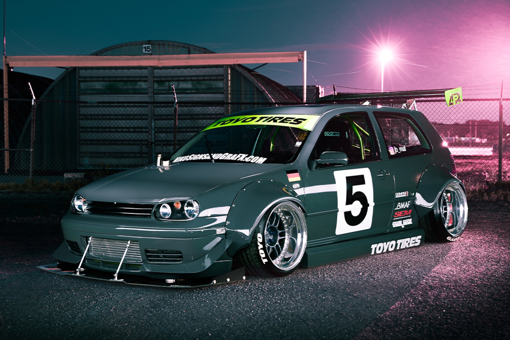 Front three-quarter hero view of Jason Bos' 2003 Volkswagen Golf GTI showing the handmade widebody, custom three-piece Enkei RPF1 wheels, Toyo Tires livery, front splitter, and aggressive stance.