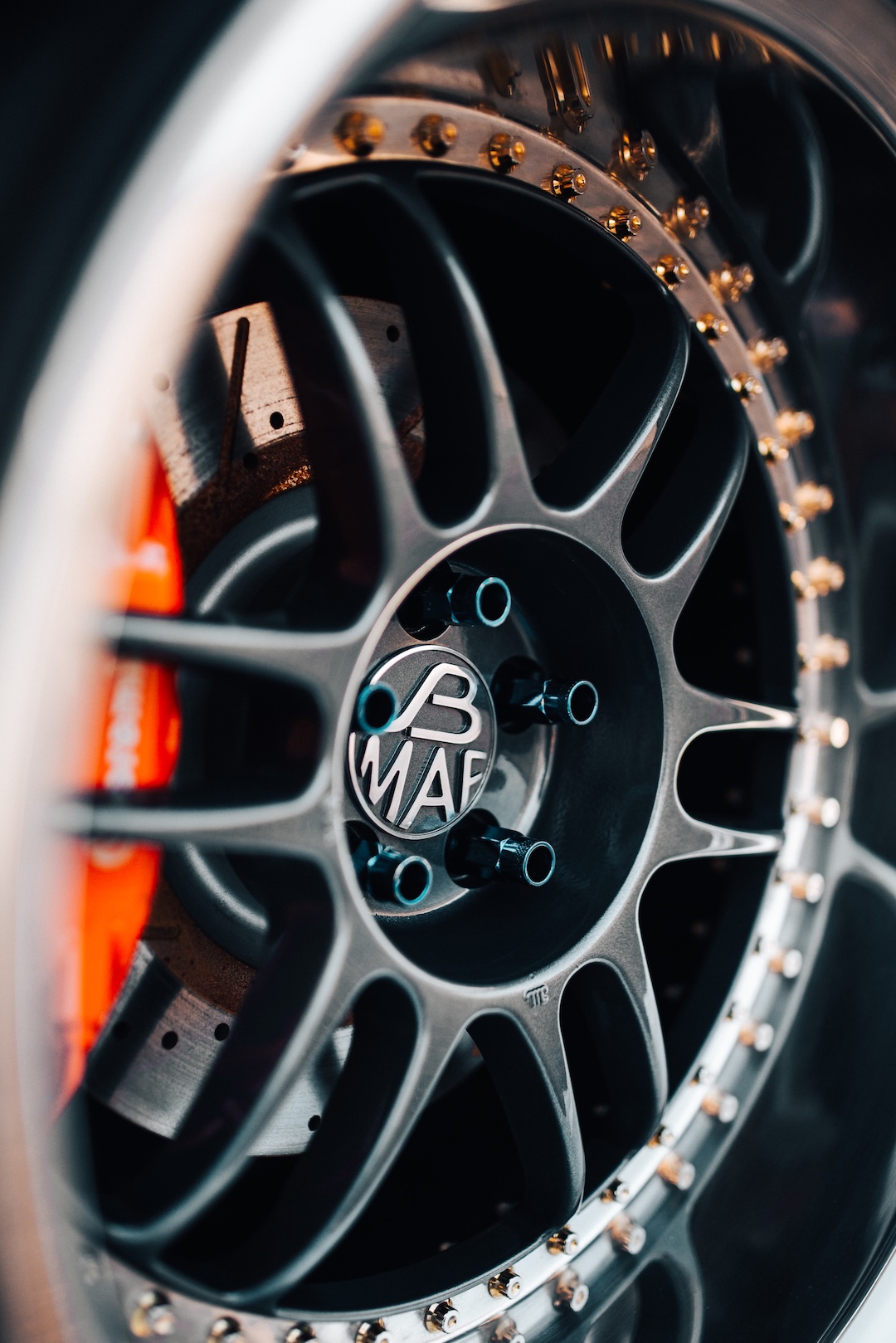 Close-up of a JB MAF wheel with polished lip, exposed hardware, center cap, and performance brake setup.