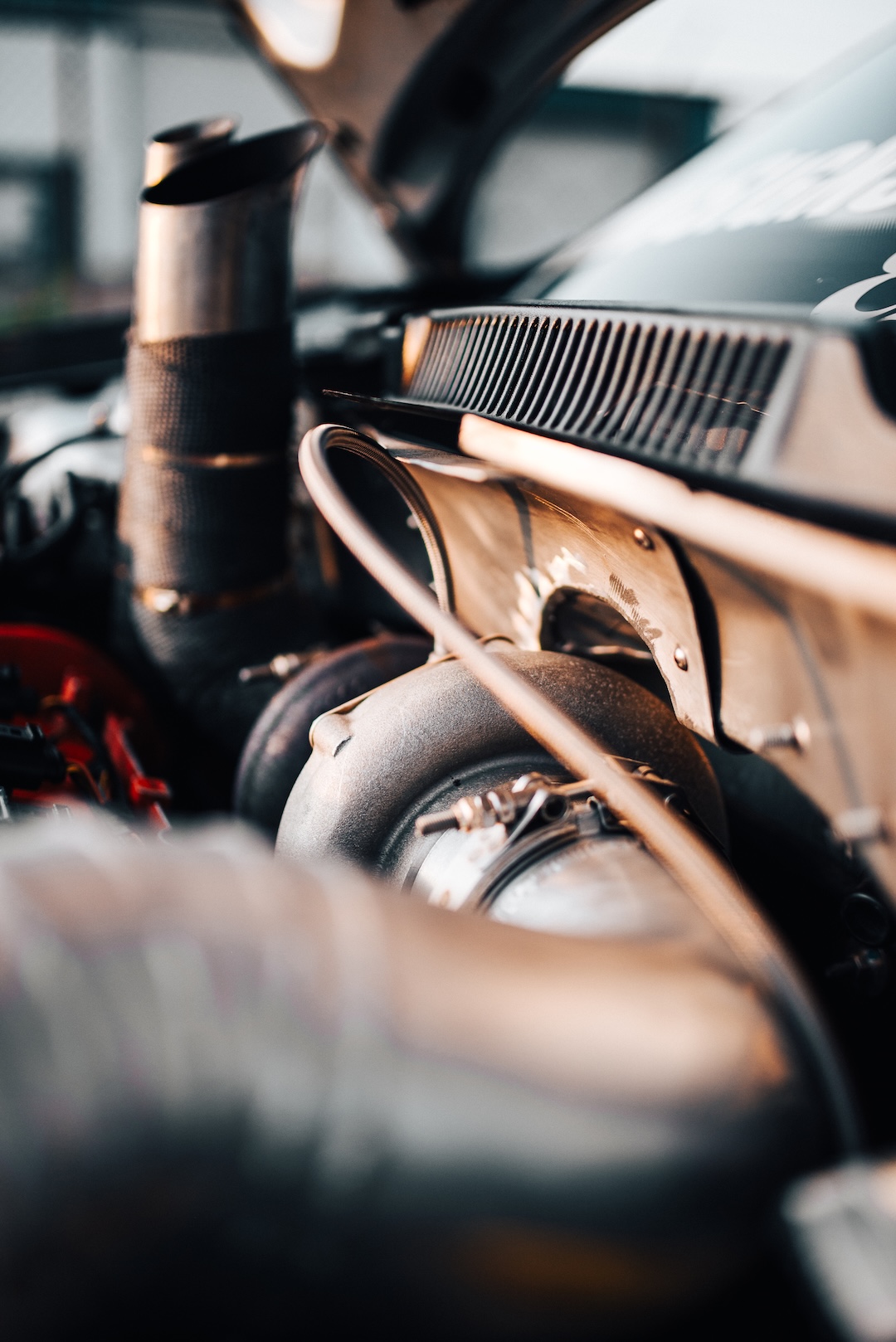 Close-up of the turbo setup on a modified Volkswagen Golf engine bay with heat-wrapped exhaust hardware.