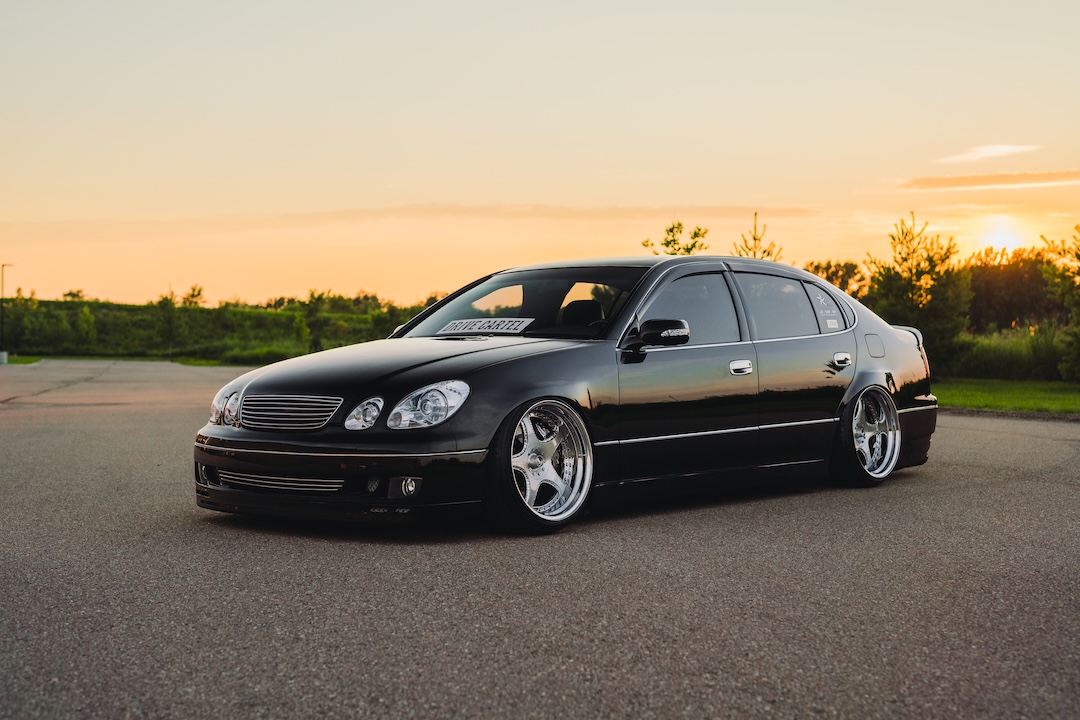 Front three-quarter view of Kyle Harty’s 1999 Lexus GS 400 showing its widened metal fenders, Luxury Abstract x Junction Produce Scara wheels, Aimgain Premium front bumper, and lowered VIP stance.