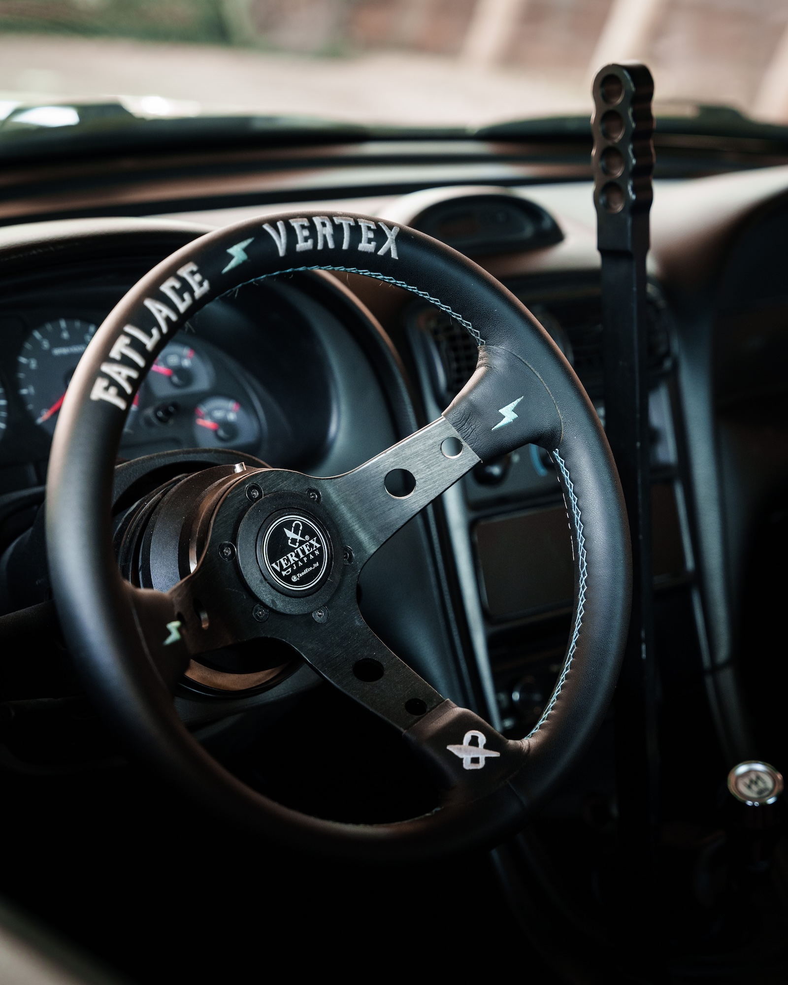 Interior of Jason Wang's 1999 Ford Mustang GT showing the Vertex x Fatlace steering wheel and custom hydraulic handbrake.